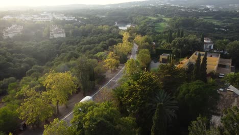 Luftbildwagen,-Der-Bei-Sonnenuntergang-Pakete-Auf-Der-Straße-Im-Wald-Fährt-Und-Liefert