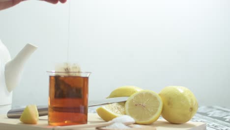 preparing green tea with lemon wedges. on wooden cutting board.