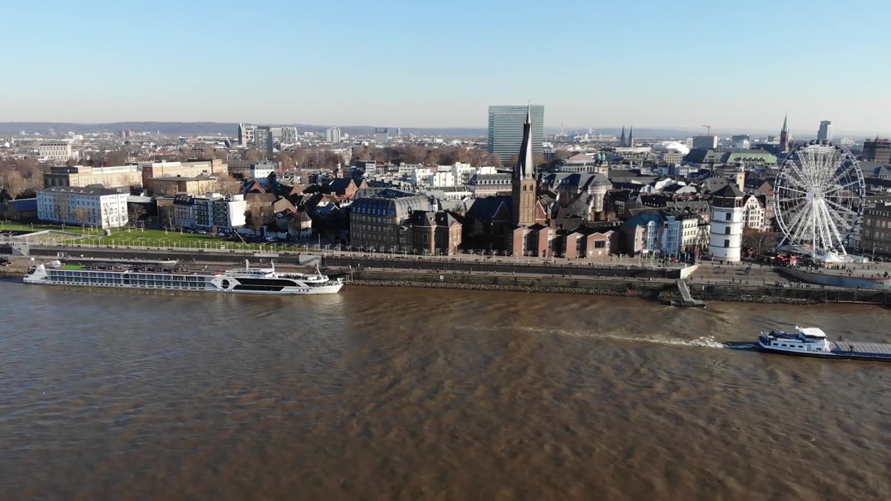 Riprese drone dell'Altstadt di Düsseldorf sul fiume Reno, centro città, con tempo invernale soleggiato, con navi che si muovono lateralmente