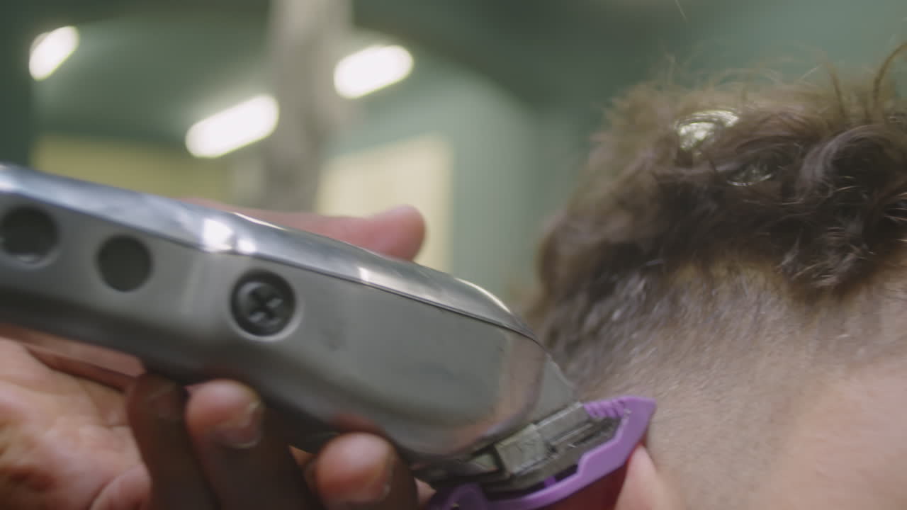 Barber Trimming Temples of Male Client with Hair Clippers