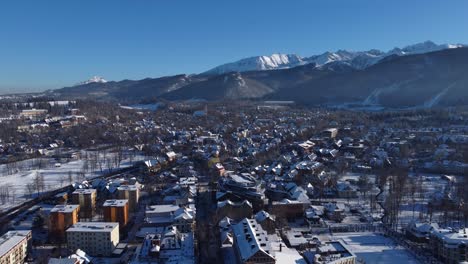 aerial view over zakopane town and main street, with snowy tatra mountains in the background - poland