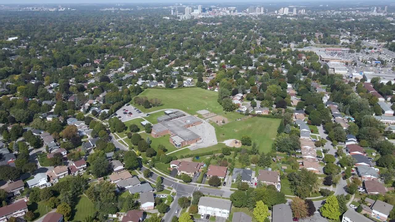 Drone flying over a school, houses and a park in London, Ontario