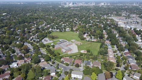Drone-flying-over-a-school,-houses-and-a-park-in-London,-Ontario