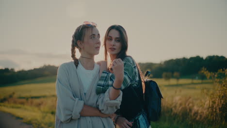 young fashionable female friends standing against sky