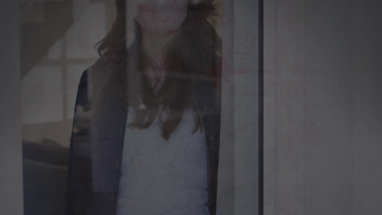 animación de la textura agrietada cambiando sobre una triste mujer biracial con máscara facial mirando por la ventana