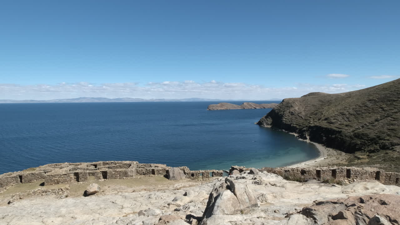 A stunning pan shot showcasing the historic Isla del Sol and its enigmatic Chincana Labyrinth on Lake Titicaca, Bolivia. The ancient Inca ruins and the serene beauty of this sacred South American site