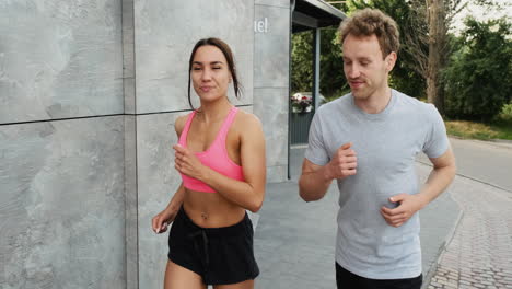 feliz pareja deportiva corriendo juntos en la ciudad