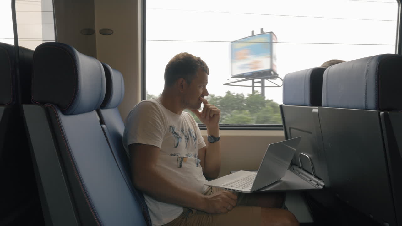 vista de un joven viajando en el tren y trabajando con una computadora portátil en la mesa contra la ventana de los países bajos