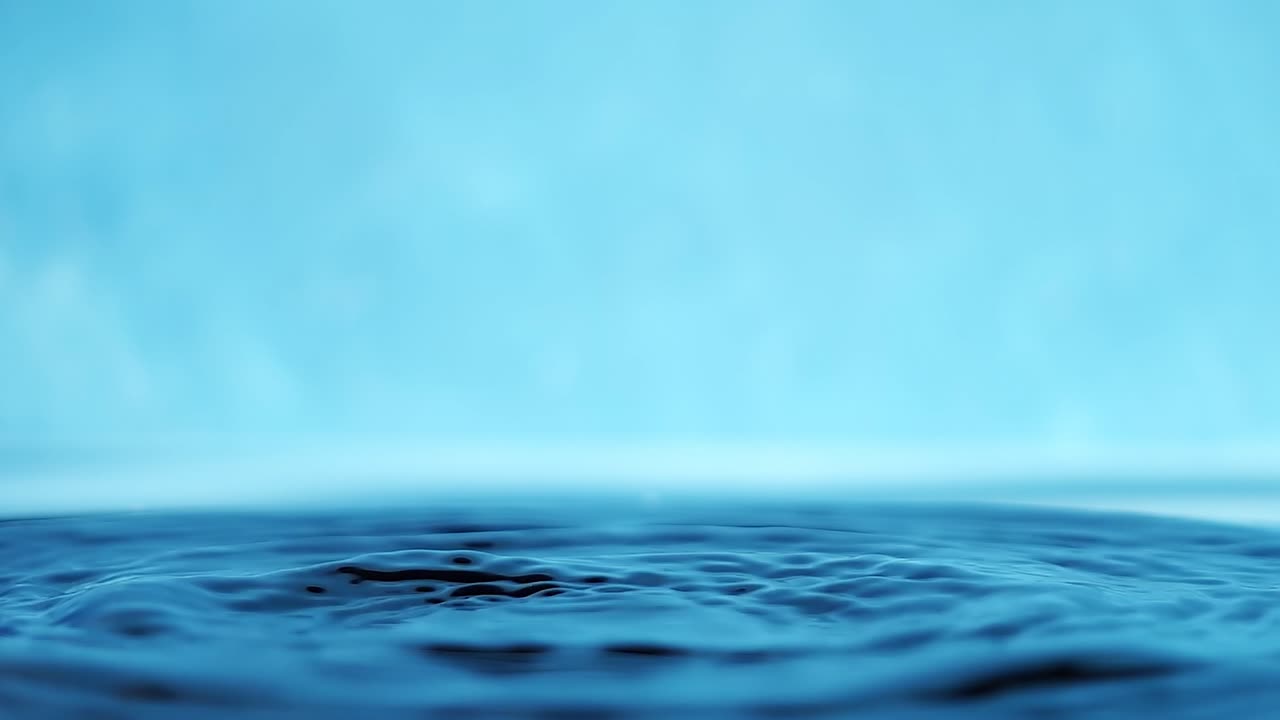 파란색 배경에 떨어지는 물방울과 함께 물 표면의 느린 모션 4k 비디오.