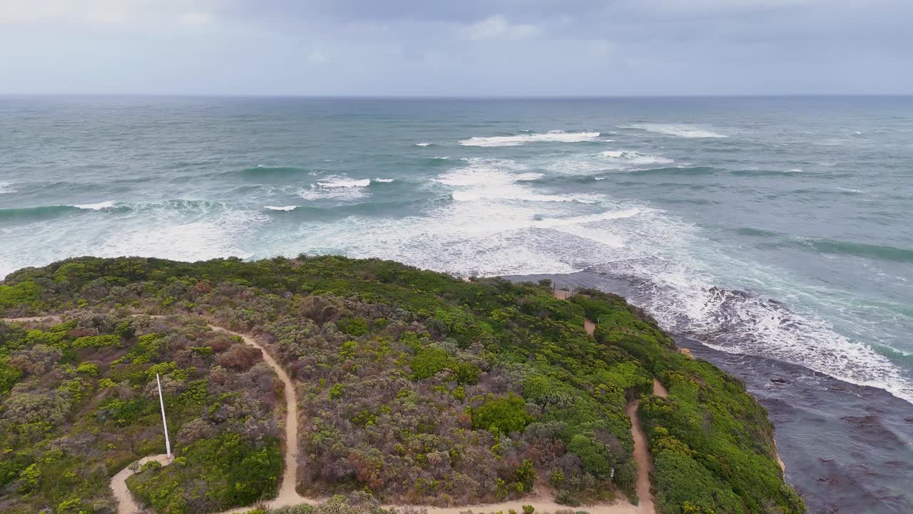 Drone captures sweeping views of Port Campbell's rugged coastline and ocean waves under cloudy skies