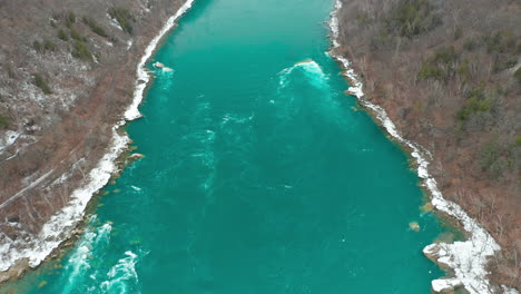 Aerial-shot-of-fast-flowing-teal-cold-river