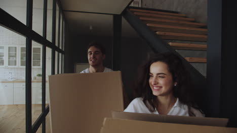 smiling man and woman putting paper boxes on floor in slow motion.