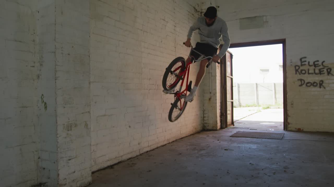 Ciclista BMX in un magazzino vuoto.