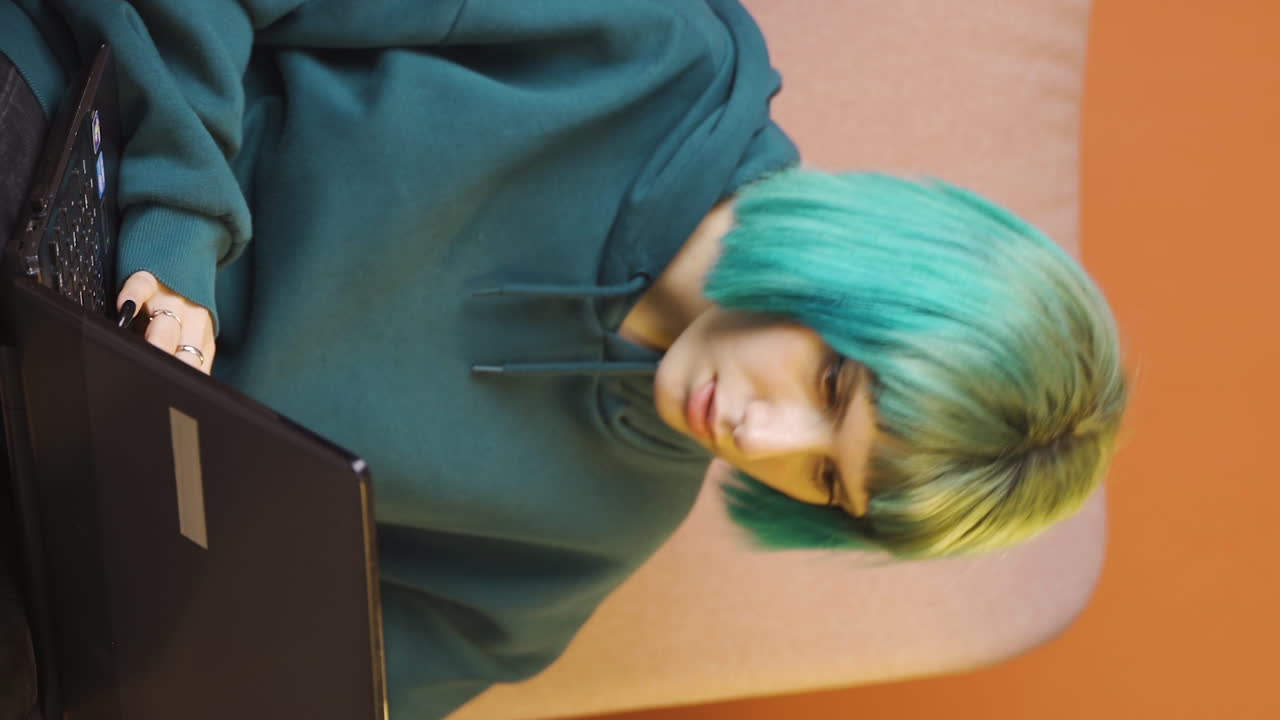 video vertical de una mujer joven trabajando duro en una computadora portátil.