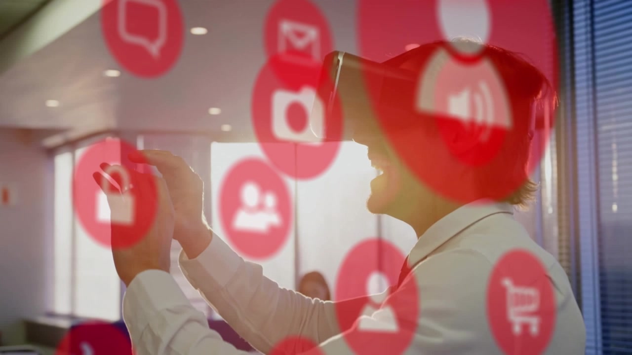Animación de iconos digitales y procesamiento de datos superpuestos a un hombre caucásico con casco de realidad virtual en una oficina.