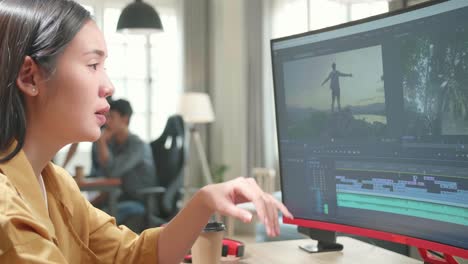 tired asian female video editor works with footage and sound on her personal computer in office