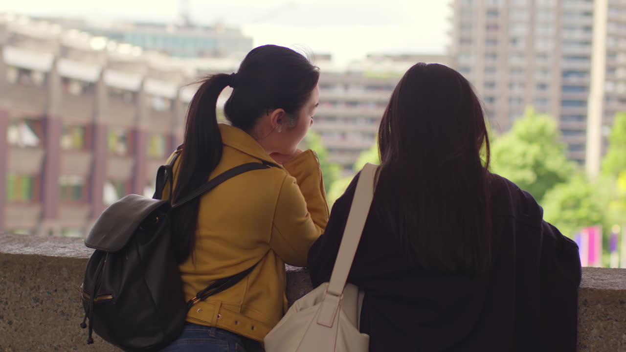 Rear View Of Two Young Female Friends Visiting The Barbican Centre In City Of London Together 1