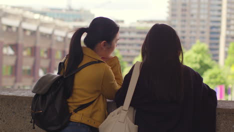 Rear-View-Of-Two-Young-Female-Friends-Visiting-The-Barbican-Centre-In-City-Of-London-Together-1