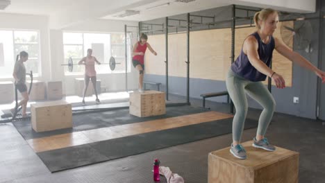 Mujeres-Diversas-Inalteradas-Saltando-Sobre-Cajas-Y-Entrenando-En-Clase-De-Fitness-En-El-Gimnasio,-Cámara-Lenta