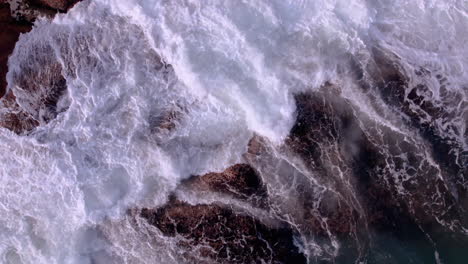 aerial view of ocean waves breaks on the rocks