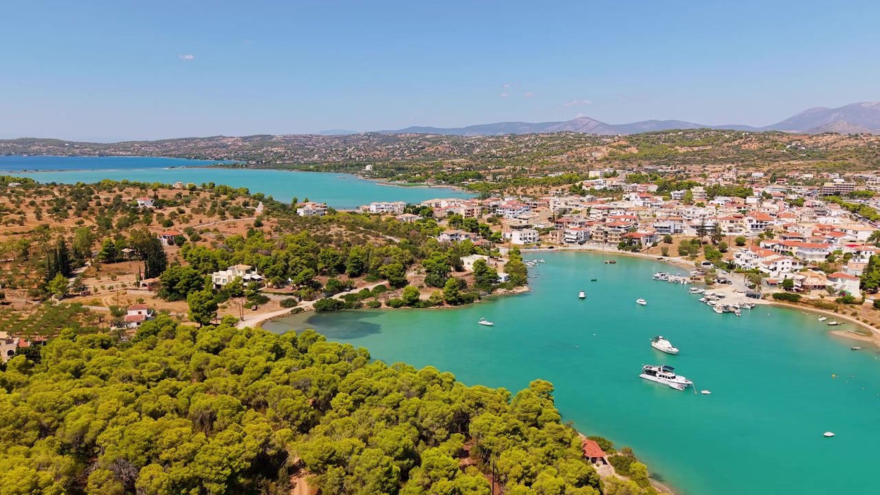 Drone, Porto Cheli üzerinde ileri doğru uçarak tüm kasabasını, korunaklı koyunu ve marinasını ortaya çıkarıyor. Parlak bir yaz gökyüzünün altında turkuaz sular, renkli çatılar ve dağlar uzanıyor
