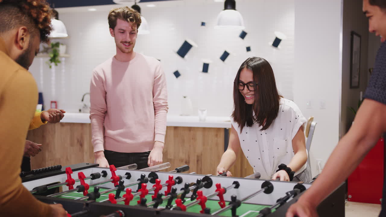 Young business creatives playing table football together at work celebrate a goal, close up