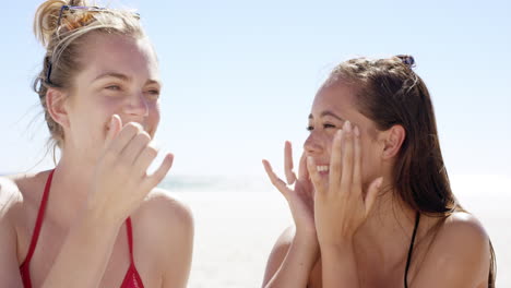 mujeres jóvenes aplicando protector solar en el cuerpo para protegerse del sol