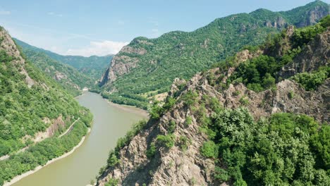 the winding olt river cutting through the verdant valleys and hills, under sunny skies, aerial view