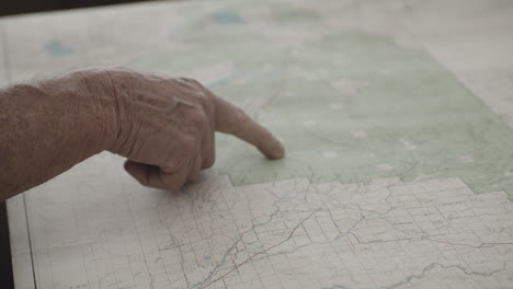Der-Zeigefinger-Des-Alten-Mannes-Bewegt-Seine-Hand-Auf-Der-Lage-Des-Westlichen-Yellowstone-Auf-Der-Papierkarte