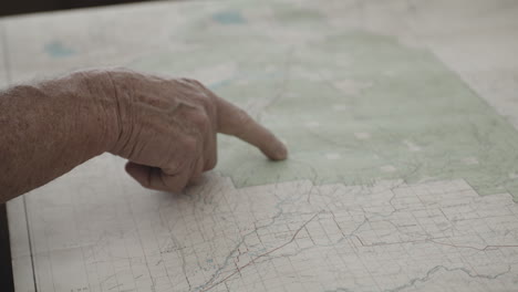 el dedo índice del anciano moviendo su mano en la ubicación de la piedra amarilla occidental en el mapa de papel