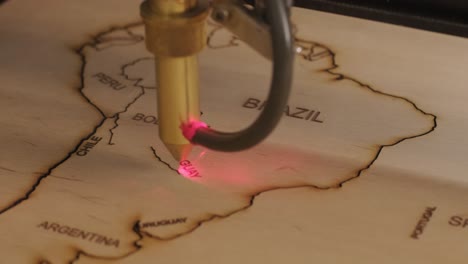 cnc laser cutting machine cuts world map on wooden plank and plywood