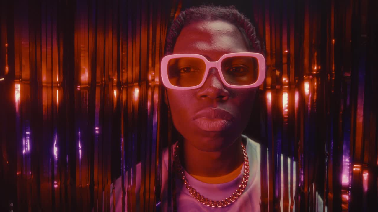 Portrait of African American Man in Trendy Glasses against Shimmering Curtains