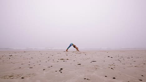 side view of a young woman doing a sun salutation on the beach