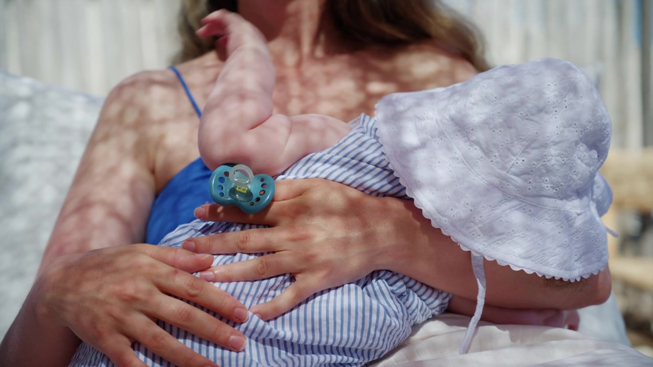 Tenero primo piano di una madre che tiene in braccio il suo bambino mentre si rilassa in una lounge di un beach club