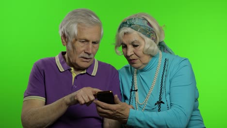 mature senior old couple grandparents enjoy online shopping on mobile phone