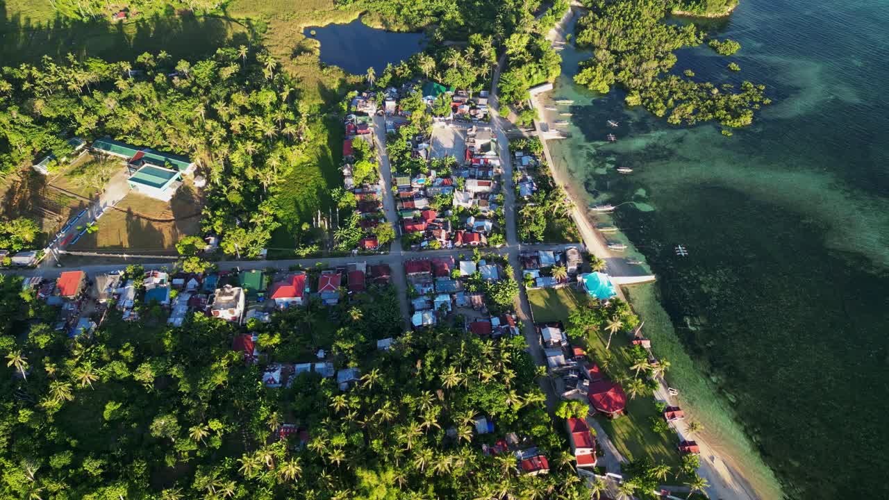 Picturesque flyover shot of rural coastal village Yocti with lush surrounding greenery at tropical island Catanduanes, Philippines