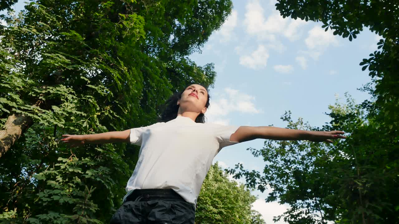 젊은 갈색은 하늘과 초록색 나무에 대항하여 자신을 둘러싸고 회전합니다.