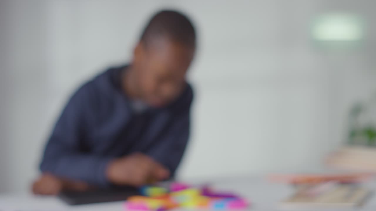 Defocused Shot Of Boy On ASD Spectrum At Home Solving Shape Puzzle Sitting At Table 1