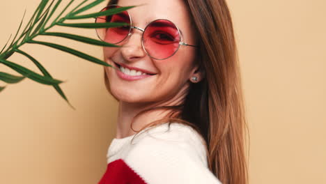 mujer con gafas de sol y hoja de palma