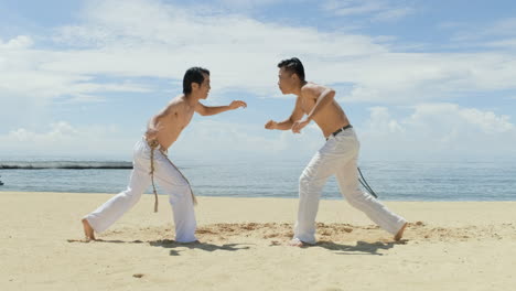 dos hombres bailando capoeira en la playa