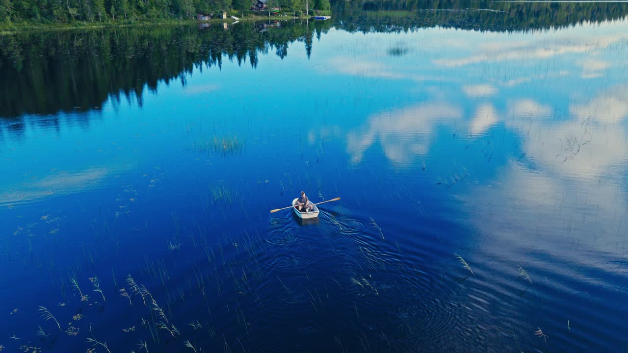 Tranquil Lake With A Man Sailing In A Rowboat. Aerial Shot