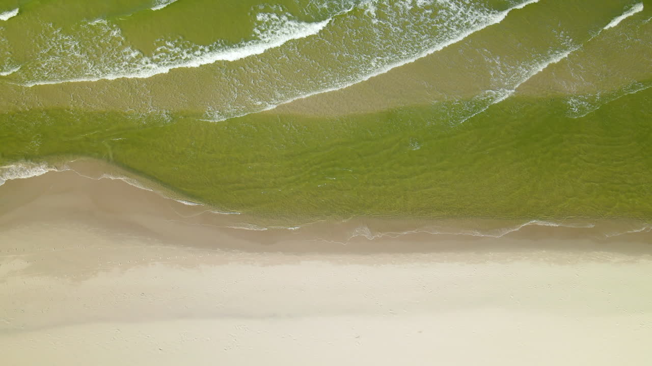 2020년 초가을 폴란드 오세트니크에 있는 빈 백사장을 향해 발트해 녹색 바닷물 거품 파도에서 천천히 아래를 가리키며