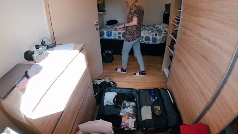 time lapse of young female packing a suitcase for travel in the room