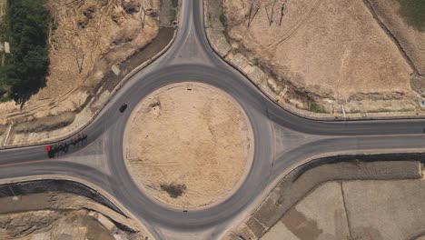 top down aerial view of a traffic roundabout. camera departure.