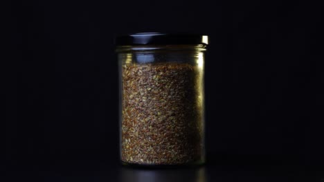 dark grains in a jar against a black background