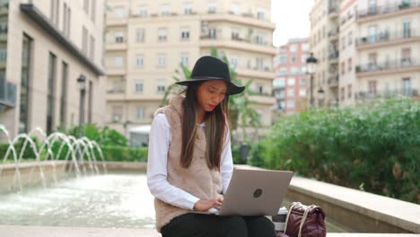 Hispanic-woman-browsing-laptop-on-street