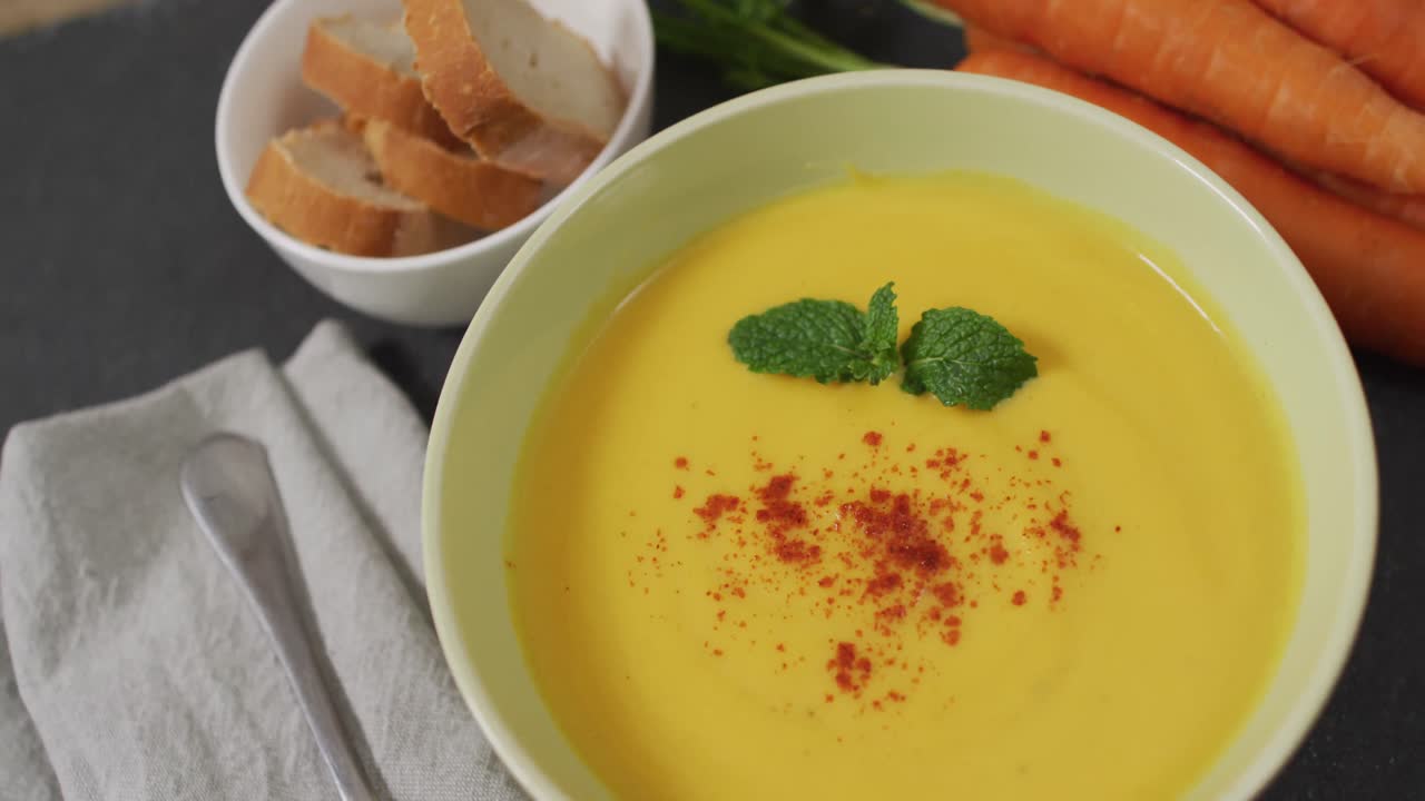 video de sopa de verduras con crema en un cuenco en una mesa gris con zanahorias