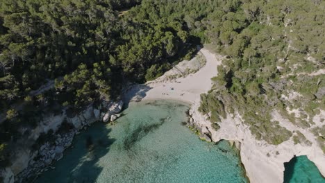 Aerial-shot-of-shallow-bay-at-Cala-Mitjana-virgin-beach-in-Menorca,-Spain