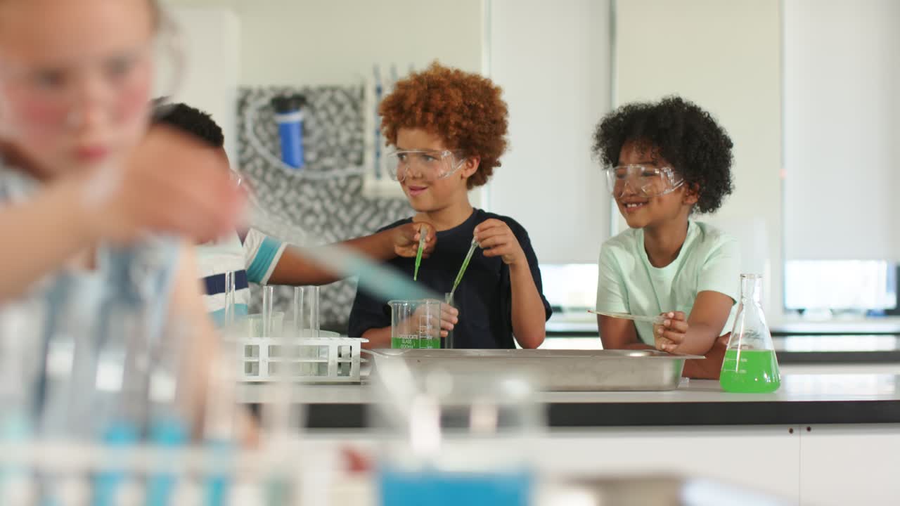 Diversi studenti adolescenti maschi in laboratorio confrontano usando contagocce mentre la telecamera si sposta dalla ragazza che usa la pipetta.
