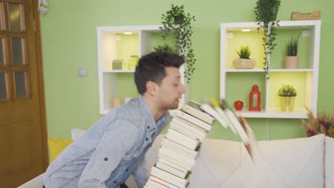 clumsy young man losing his balance while carrying stack of books at home. misfortune.